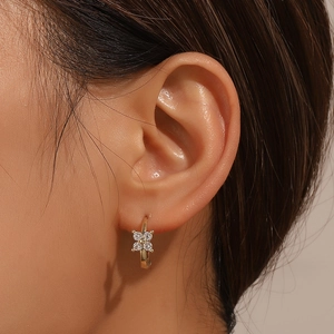 Elegant gold four-leaf clover hoop earrings with crystal pavé on a female ear model