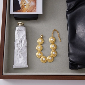 Elegant 18K gold plated stainless steel bracelet with white pearls on a grey velvet tray