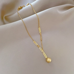 Detail of matte gold ball pendant on a textured link chain made of titanium steel