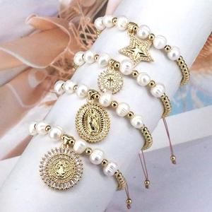 Detail of four-piece pearl bracelets with star, cross, and Virgin Mary charms on stand