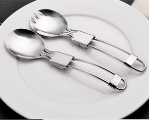 Close-up of portable stainless steel folding spoon and spork set on a white plate