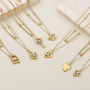 Detail of gold heart and crown pendants with crystals on a delicate beaded chain