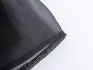Dettaglio dell'abito in organza nera con tessuto strutturato e bordo in tulle a balze fini