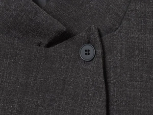 Close-up of charcoal gray blazer fabric with a black matte button and fine stitching detail
