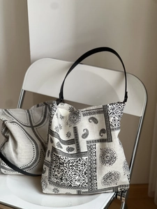 Close-up of ethnic paisley print tote bag with black leather straps on a white chair
