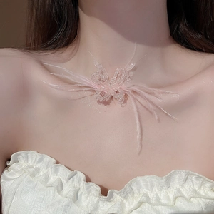 Detail of pink feather butterfly necklace on model's neck with beaded chain texture