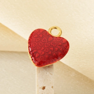 Detailed close-up of a red enamel heart charm with gold-plated edging and a round bail
