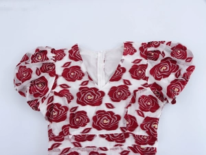 Detailansicht des V-Ausschnitts und der roten Rosen-Jacquard auf dem weißen Netzkleid