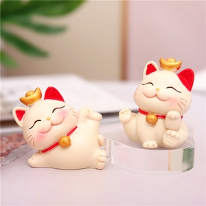 Close-up of cute white lucky cat figurines with golden bells for car or desk decor