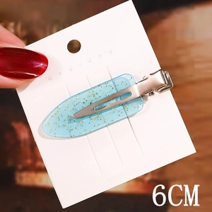 Close-up of a 6cm blue gradient acetate hair clip with gold glitter on a display card