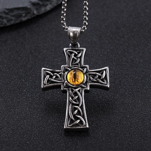 Macro shot of Gothic steel cross pendant with yellow dragon eye and Celtic knotwork