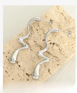 Macro detail of silver wavy liquid metal earrings with a polished mirror finish on stone