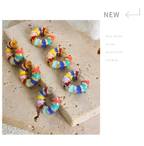 Close-up of colorful enamel striped hoop earrings displayed on textured stone