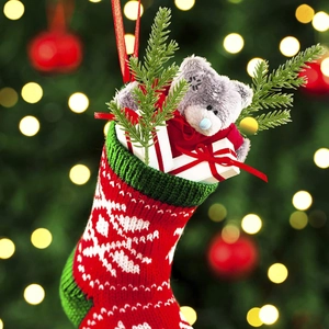 Festive knitted Christmas stocking with plush bear and pine branches in warm holiday setting