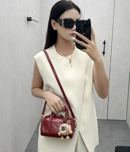Detail of burgundy glossy leather Boston bag with plush bear charm and gold hardware