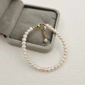 Elegant white freshwater pearl bracelet with gold lobster clasp on velvet jewelry box