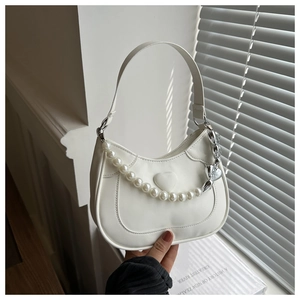 Close-up of white saddle bag featuring embossed heart and elegant pearl chain detail