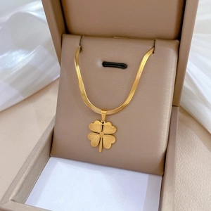 Gold titanium snake chain necklace with a four-leaf clover pendant in a jewelry box