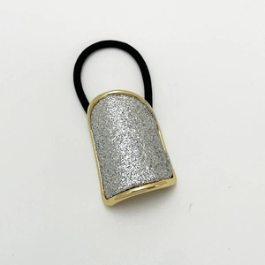 Detail of U-shape hair tie with gold metal frame and silver glitter finish on white background