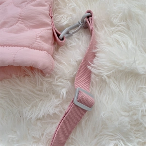 Detail of pink quilted nylon bag showing wave stitching and adjustable plastic strap buckle