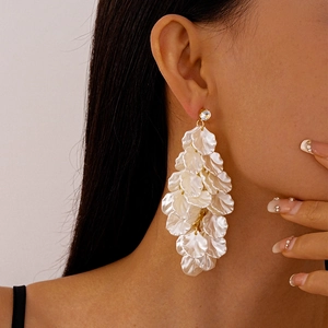 Detail shot of white acrylic petal tassel earrings with gold zircon stud on model