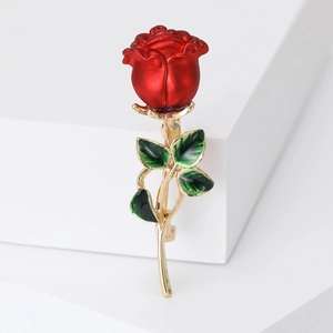 Detail view of a stylish rose brooch featuring red petals and green leaves on golden stem