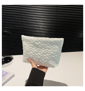 Close-up of white bubble quilted fabric texture on a stylish women clutch bag