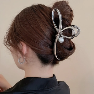 Detail of silver metal hair claw with pearl accent on model's dark hair