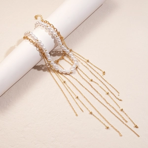 Close-up of a double-layered pearl necklace with golden tassels on a white display stand
