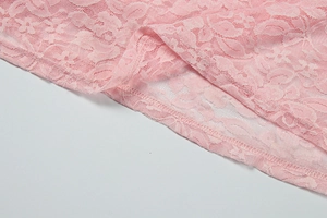 Detail view of pink floral lace fabric with neat three-thread overlock stitching