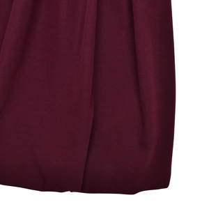 Dettaglio ravvicinato del tessuto bordeaux con trama ricca e drappeggio elegante dell'abito