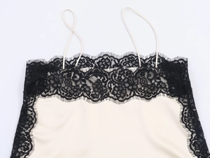 Detail of cream silk camisole featuring delicate black lace trim and thin straps