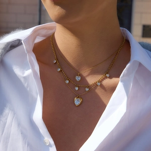 Gros plan de colliers dorés à trois couches avec pendentifs cœur en zircon sur mannequin