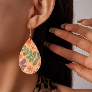 Détail de boucle d'oreille goutte en liège avec motif floral violet et vert et crochet d'or