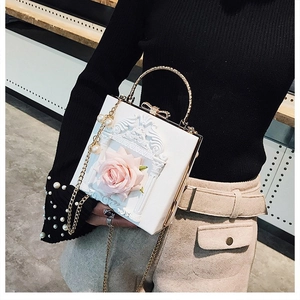 Detailed view of white floral box bag with 3D pink rose and elegant column relief patterns