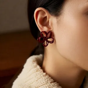 Elegant deep red hollow flower stud earrings in matte finish worn by female model