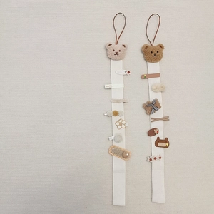Dual bear hair clip organizers in cream and brown fabric hanging with cute accessories