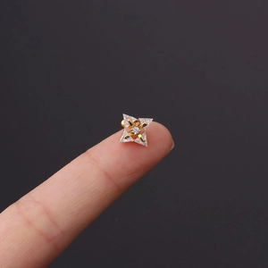 Macro detail of a gold-plated star earring with zircons held for scale by hand
