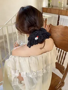 Close-up of a polka dot ruffle scrunchie with a red heart button in soft chiffon fabric