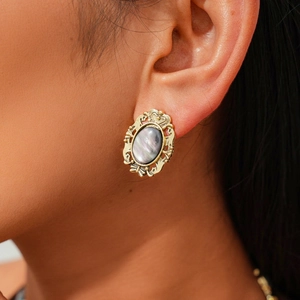 Close-up of vintage Baroque oval earrings with ornate gold engraving and resin inlay