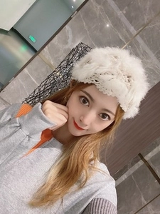 Close-up of white crochet beanie featuring soft rabbit fur trim and intricate hollow floral knit