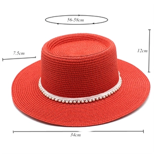 Detail view of red straw boater hat with pearl strap showing dimensions and weaving