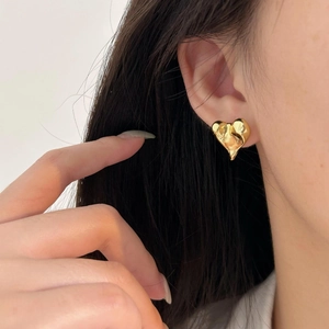 Asymmetrical gold lava heart studs on a model with minimalist irregular design