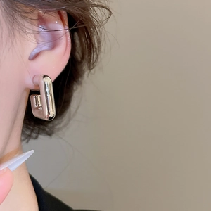 Gros plan de boucles d'oreilles carrées en argent minimalistes portées par un mannequin