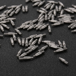 Precision stainless steel threaded pins and machined hardware components on black background