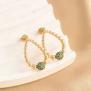 Eleganti orecchini a goccia dorati con perle di zircone verde su sfondo di seta