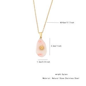 Detail view of irregular pink natural stone pendant with gold sunburst on stainless steel chain