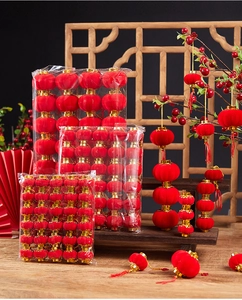 Close-up of mini red flocked lanterns hanging on festive branches with golden tops