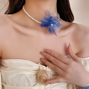 Close-up of pearl necklace with blue gradient mesh flower on a model's neck