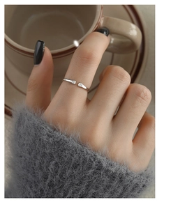 Close-up of a silver cat paw wrap ring worn with a cozy grey sweater and coffee cup